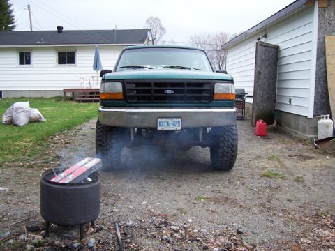 1996 Ford Bronco - A lifted green Ford Bronco is parked in a driveway, emitting smoke from its exhaust.