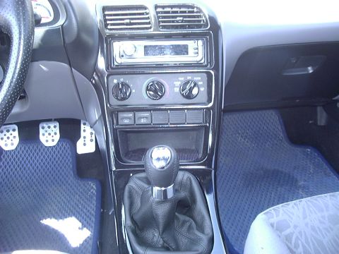 1995 Ford Probe - Close-up of a car's interior, showing the center console with a manual transmission shifter and dashboard controls.