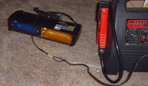 1997 Ford Crown Victoria - A car headlight assembly and a jump starter are shown on a carpeted surface.