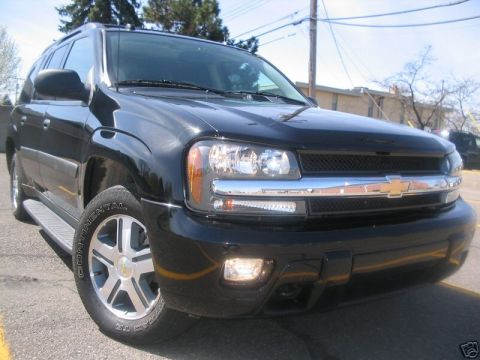 1998 Ford Crown Victoria - This black SUV is parked on a street with trees and buildings in the background.