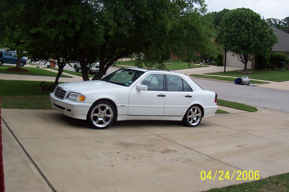 White Mercedes-Benz C-Class sedan with chrome wheels parked in a driveway