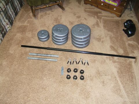 1998 Ford Taurus - Weightlifting equipment including plates, a barbell, and collars is arranged on a carpeted surface.