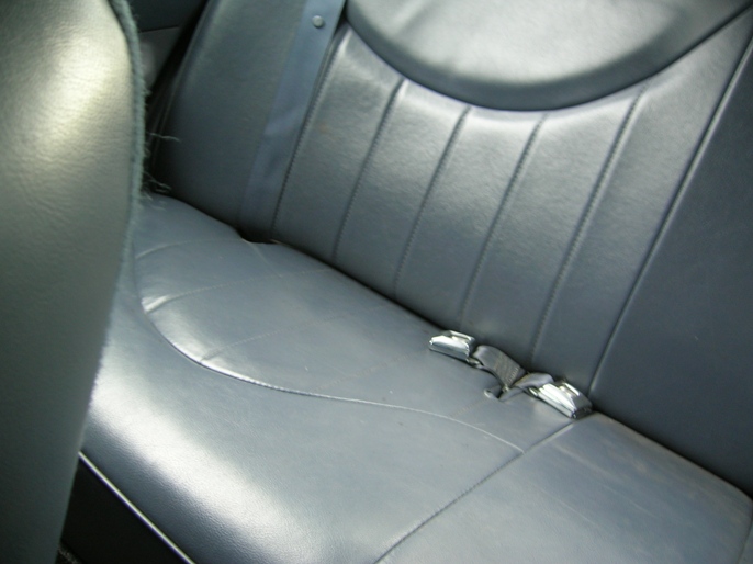 Gray leather rear car seat with a seatbelt buckle visible