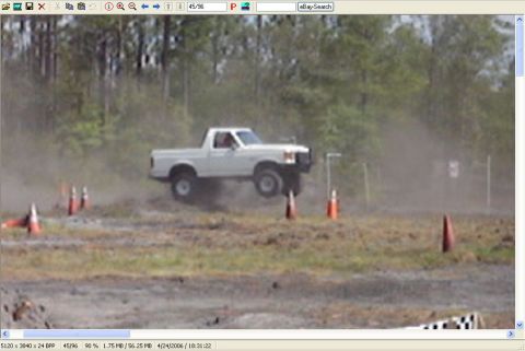 1989 Ford Bronco - A white 1989 Ford Bronco pickup truck is captured mid-air during an off-road event.