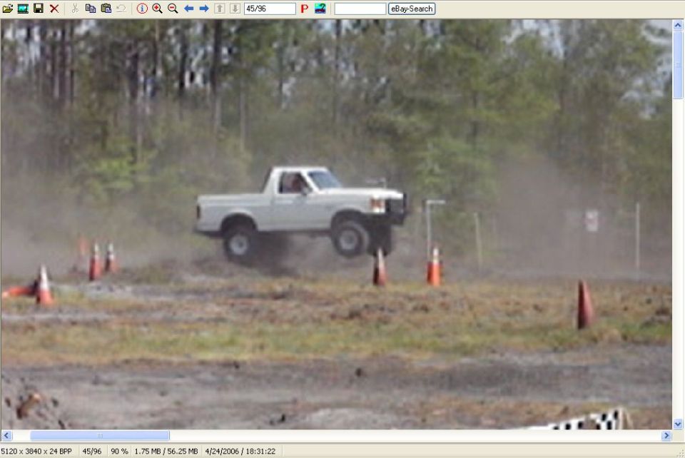 White 1989 Ford Bronco pickup truck airborne over dirt track