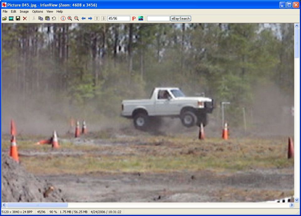 White pickup truck airborne over orange cones, dust in the air