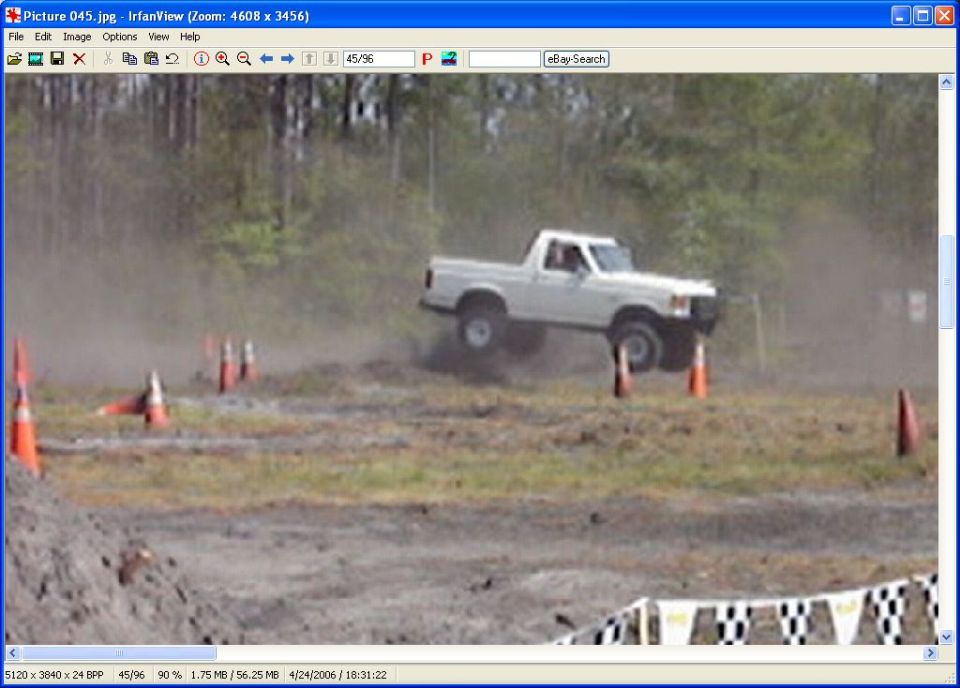 White pickup truck jumping over dirt track with orange cones