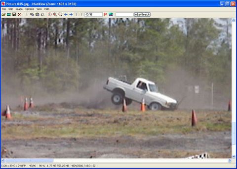 1989 Ford Bronco - A white pickup truck navigates a dusty off-road course, marked by orange cones.