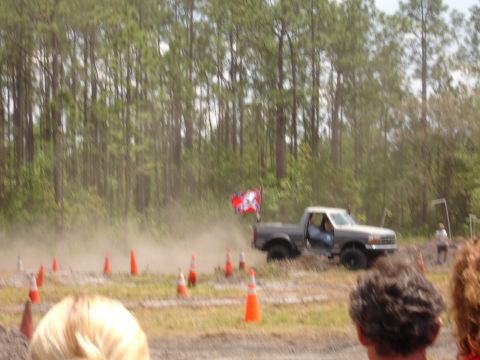 1989 Ford Bronco - Pickup truck navigates a dirt course marked by orange cones, with trees in the background.