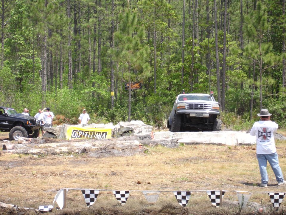 1989 Ford Bronco navigating an off-road obstacle course with a black Jeep nearby
