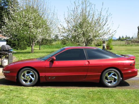 1997 Ford Probe - A dark red Ford Probe GT two-door hatchback coupe shown in profile from the driver's side, with chrome five-spoke wheels, tinted windows, a…