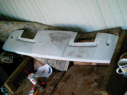 White fiberglass rear panel or valance laid across a wicker couch indoors