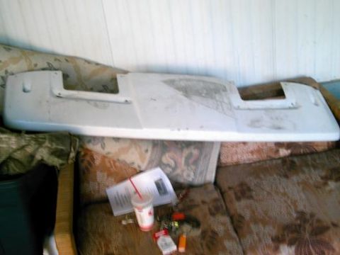 1986 Ford Bronco - A white vehicle visor is resting on a couch next to a cup and some papers.
