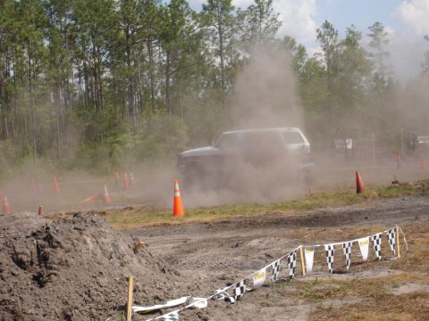 1989 Ford Bronco - An SUV navigates a dusty off-road course marked by cones and checkered flags.