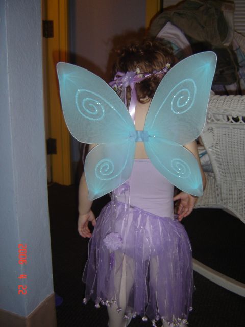 1993 Ford Bronco - A child dressed as a fairy stands indoors, with large blue wings spread out.