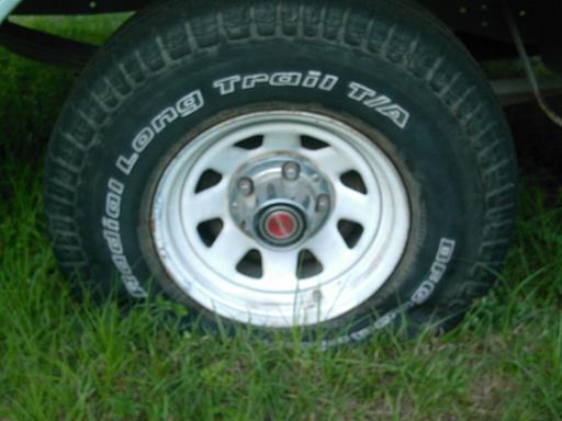 White steel wheel with red center cap on a Radial Long Trail T/A tire mounted on a vehicle in grass