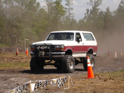 1989 Ford Bronco - This lifted SUV, likely a 1992 Ford Bronco, navigates a dusty off-road course.