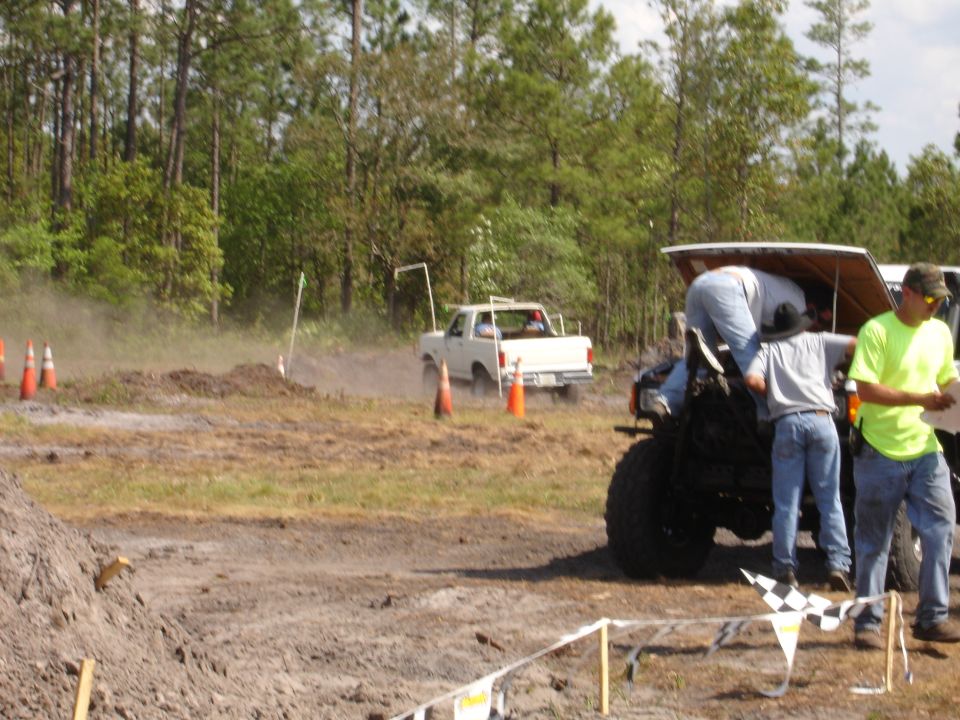 White pickup truck driving through mud, rear view