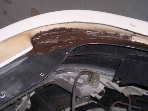 1996 Ford Probe - Body filler is applied to a damaged car fender seam during a repair.