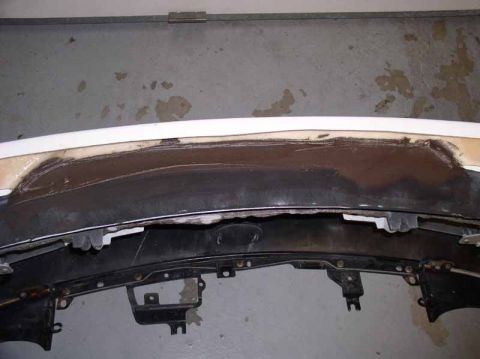 1996 Ford Probe - Close-up of a damaged car bumper, revealing repair efforts and exposed internal components.