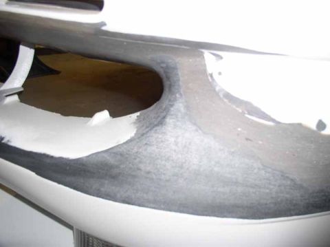 1996 Ford Probe - This image shows a close-up of a car bumper undergoing repair, with visible primer and body filler applied.