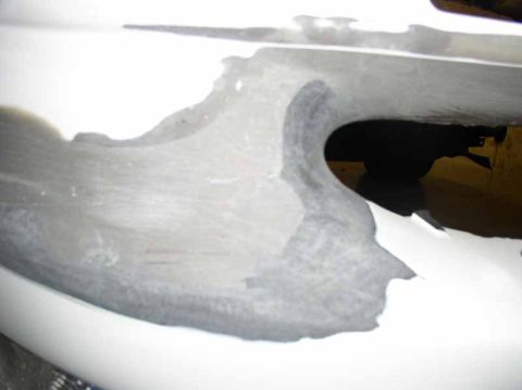 1996 Ford Probe - Close-up of a damaged white car bumper with visible primer and rough texture.