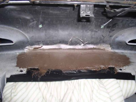 1996 Ford Probe - A close-up view shows a section of a black plastic panel undergoing repair with putty and mesh.