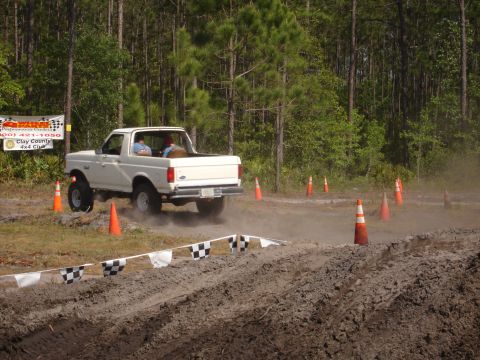 1989 Ford Bronco - A white pickup truck navigates a dusty off-road course with orange cones marking the path.