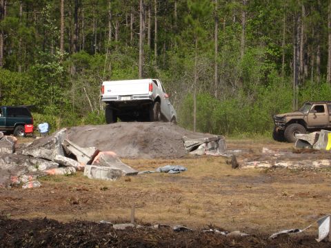 1989 Ford Bronco - A white pickup truck navigates an obstacle course, with another vehicle visible in the background.