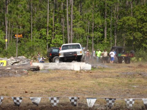 1989 Ford Bronco - Multiple off-road vehicles navigate a challenging course with spectators watching.