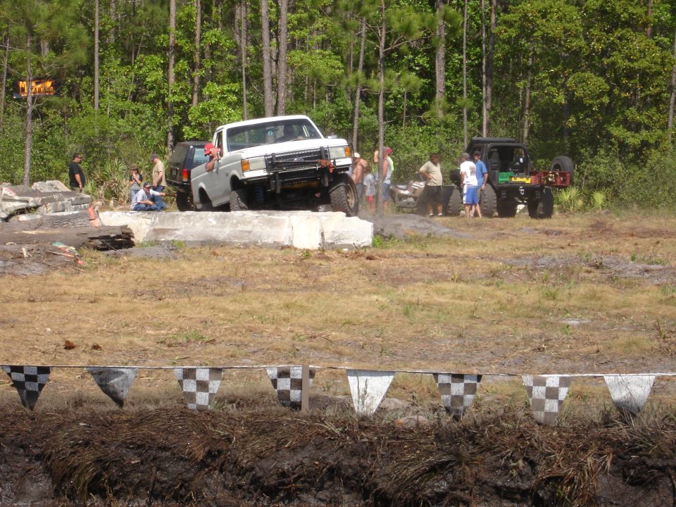 White pickup truck with a brush guard on a concrete obstacle, front 3/4 view
