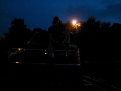1986 Ford Bronco - Night shot of a person on a truck's hood, with trees and a light pole in the background.