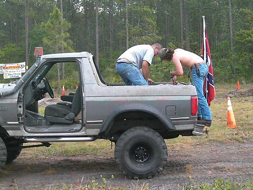 Gray 1986 Ford Bronco side view with two men working in the bed