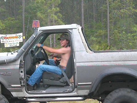 1986 Ford Bronco - Driver in a Ford Bronco with snorkel and off-road lights, seen from the side.