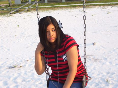 1994 Ford Probe - A young girl sits on a swing set in a sandy area, looking off to the side.