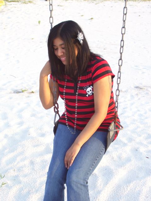1994 Ford Probe - A woman wearing a red and black striped shirt with a skull graphic sits on a swing.