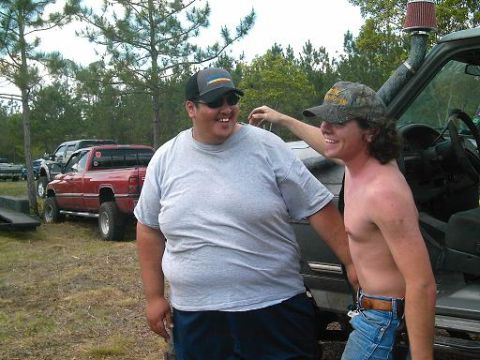 1986 Ford Bronco - Two men stand by a lifted truck with a snorkel intake, with other trucks visible in the background.