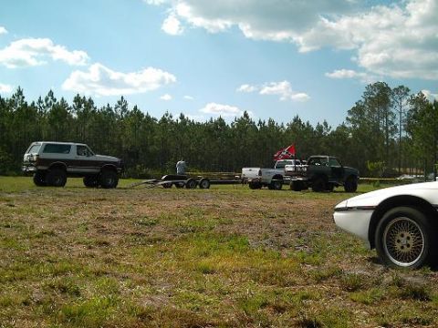 1986 Ford Bronco - A lifted Ford Bronco is parked in a grassy field with trees in the background.