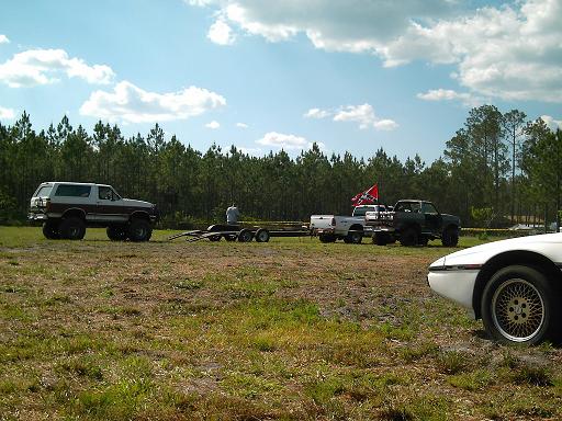 Brown and white Ford Bronco with lifted suspension parked on grass, towing a trailer