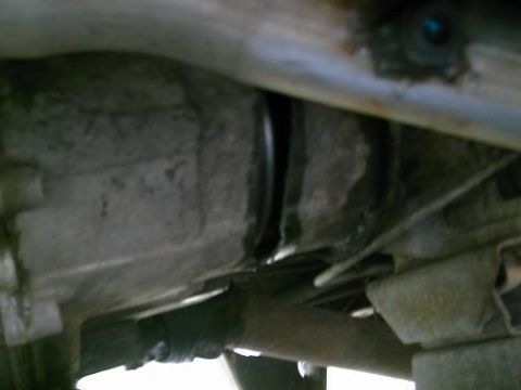 1986 Ford Bronco - The underside of a vehicle reveals its drivetrain, including the transmission and exhaust system.