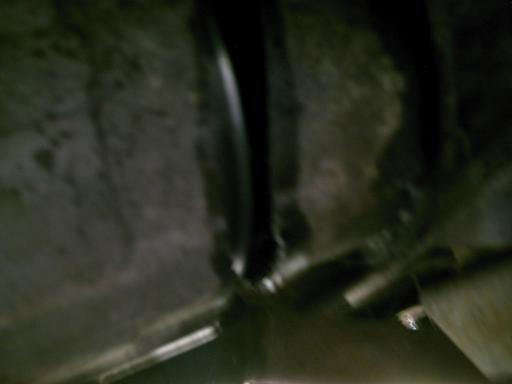 Underside view of a vehicle, showing some mechanical parts and the frame. It's dark and hard to make out details