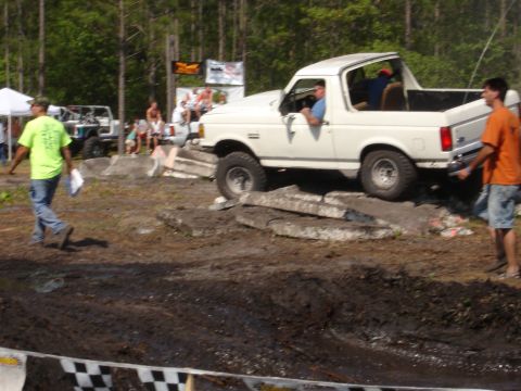 1989 Ford Bronco - A white 1989 Ford Bronco navigates an off-road obstacle course during an event.