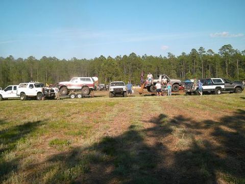 1986 Ford Bronco - Off-road vehicles are parked in a field on a sunny day.