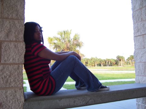 1994 Ford Probe - A woman sits on a ledge, looking out at a landscape with palm trees under a bright sky.
