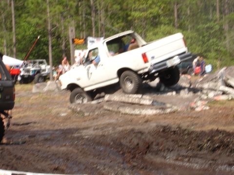 1989 Ford Bronco - White 1987 Ford Bronco is shown off-roading over rocks and mud.
