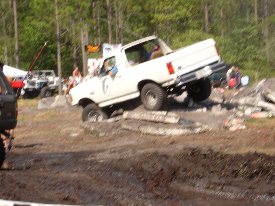 White 1987 Ford Bronco with a lifted suspension navigating an obstacle course