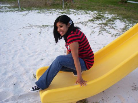 1994 Ford Probe - A young girl in a striped shirt and jeans sits on a yellow slide at a playground.