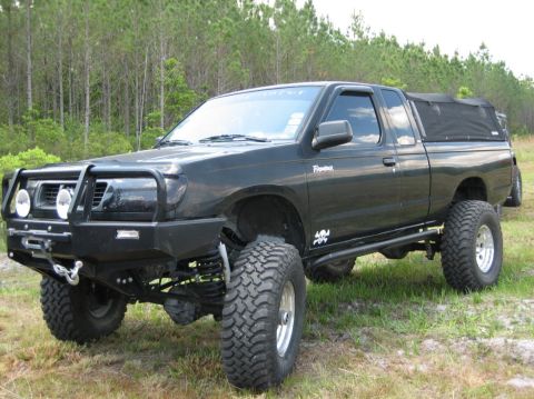 1989 Ford Bronco - This modified pickup truck features large off-road tires, a custom bumper with a brush guard, and a soft tonneau cover.
