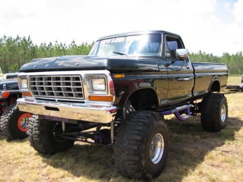1989 Ford Bronco - This lifted black Ford pickup truck, likely from 1979, features oversized tires and a prominent chrome grille.