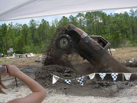 1989 Ford Bronco - A truck is stuck in a mud pit during an event, with a person filming it.